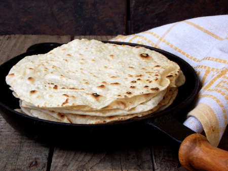 stack of pita bread in a frying pan on a wooden backgroundの写真素材