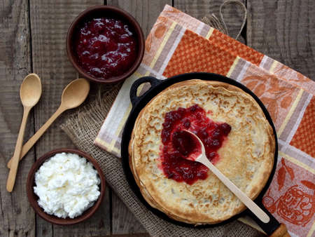 pancakes with cottage cheese and jam on a wooden background. Maslenitsa.