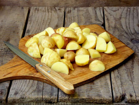 sliced raw potatoes and knife on a wooden backgroundの写真素材