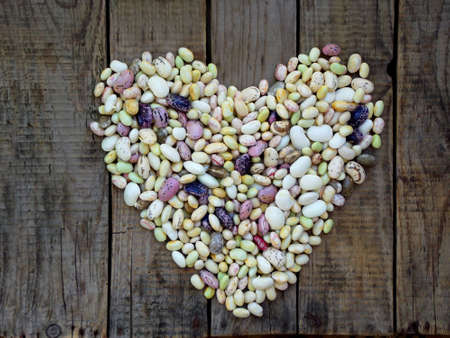 heart from beans of different varieties and colors on a wooden background.の写真素材