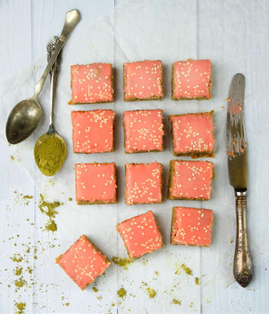 Green cakes with Japanese tea matcha covered chocolate pink frosting on light wooden background.の写真素材