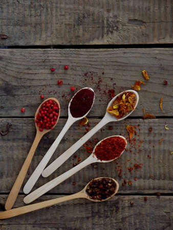 Red spices sumac, paprika marigold pepper on a wooden background.の写真素材