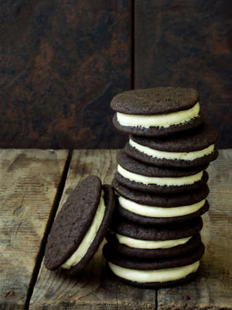 Homemade chocolate cookies with white marshmallow cream on dark background. Selective focus. Copy spaceの写真素材