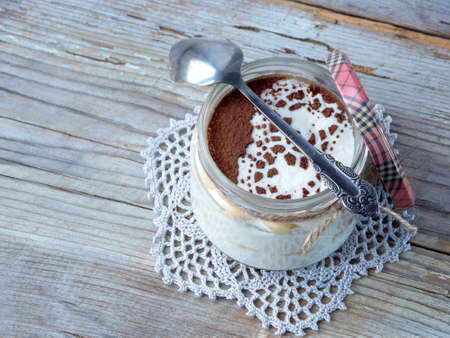Classic delicious italian cheese dessert Tiramisu in glass jar on light wooden background.の写真素材