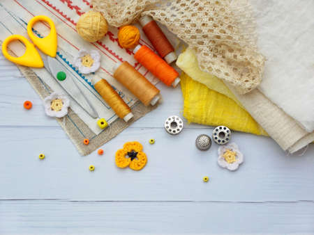 Composition of yellow accessories for needlework on wooden background. Knitting, embroidery, sewing....