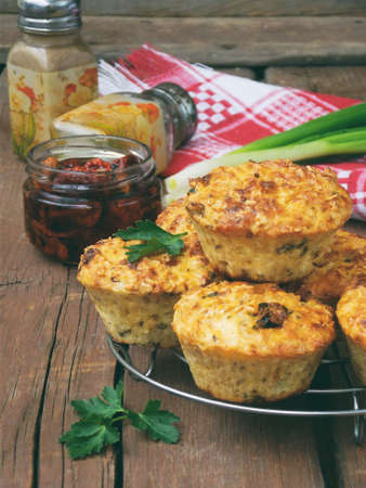 salty snack cakes muffins with cheese, tomatoes and parsley on wooden background - selective focusの写真素材
