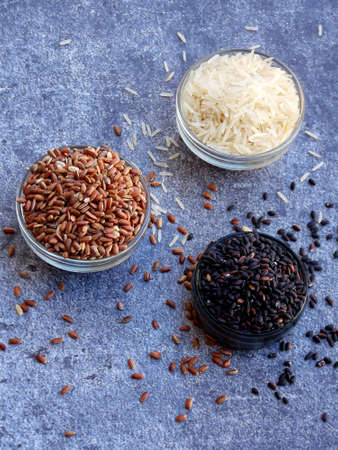Set of different types rice on grey background: white glutinous, black, basmati, brown and mixed rice. Healthy concept. Top view. Copy spaceの写真素材