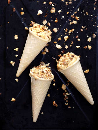 caramel ice cream cone topped with caramelized walnuts on a black backgroundの写真素材