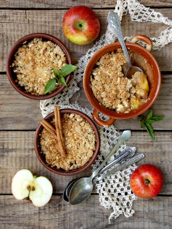 Cheese casserole or crumble with apples and cinnamon in brown cup ramekin on wooden backgroundの写真素材