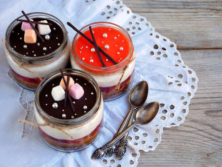 Cheesecake dessert in glass jar on wooden background.: chocolate biscuit, salted caramel, strawberry...
