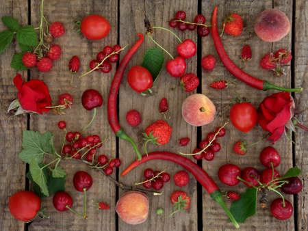 red fruits, vegetables and flowers on wooden background - currants, raspberries, strawberries, strawberry, peach, pepper, chilli, tomato, rose, cherry,の写真素材