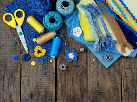 yellow and blue accessories for needlework on wooden background. Knitting, embroidery, sewing. Small business. Income from hobby.の写真素材