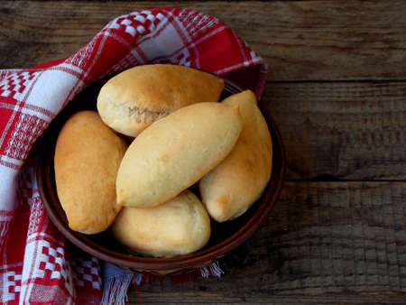 Pies with cabbage in a clay plate on a brown wooden backgroundの写真素材