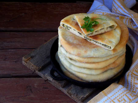 pile of Georgian pies with cheese and spring greens on a wooden background. Space for textの写真素材