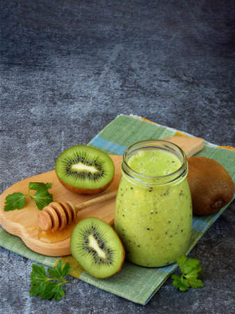 Healthy green smoothies from kiwi, oatmeal, nuts and honey on dark background.の写真素材