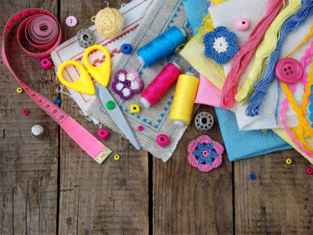 Pink, yellow and blue accessories for needlework on wooden background. Knitting, embroidery, sewing. Small business. Income from hobby.の写真素材