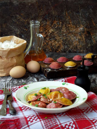 Fresh pink yellow beet dumplings or ravioli stuffed with ricotta cheese with butter sauce on wooden board on dark background. Space for textの写真素材