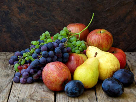 still life of autumn fruits: grapes, apples, pear, plum on a wooden background. selective focusの写真素材