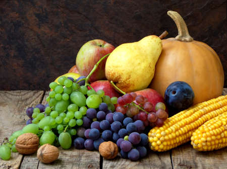 still life of autumn fruits and vegetables like grapes, apples, pears, plums, pumpkin, corn nuts on a wooden background. selective focusの写真素材
