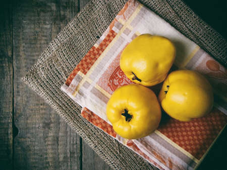 Three ripe yellow quince on a wooden backgroundの写真素材