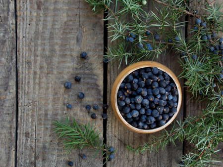 Juniper berries in a small bowl on a wooden backgroundの写真素材