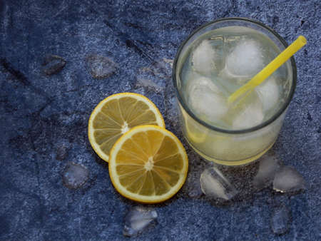 glasses of cold homemade lemonade with lemon slices, ice cubes and straws on dark background. Copy space.の写真素材