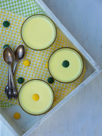 Yellow dessert Junket from milk and rennet extract with turmeric in glasses on light background. Jelly-like pudding made from sweet cottage cheese. Healthy food. Space for text.の写真素材