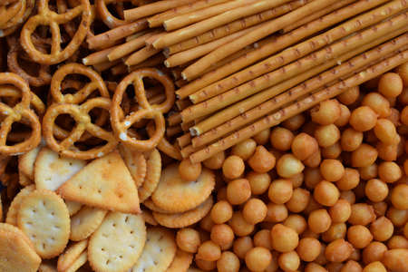 Salty snacks. Crackers, pretzel, salted straws, nuts. Junk food for beer or cola. Photographed with natural light.の写真素材