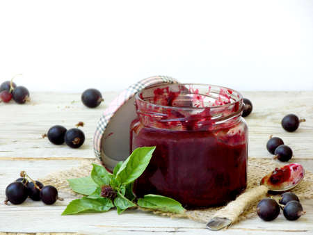 One jar of jam from the black currant on a wooden background. Berries frayed with sugarの写真素材