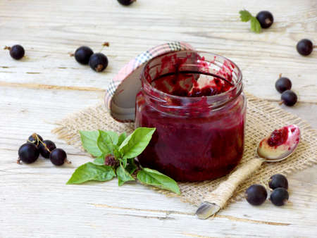 One jar of jam from the black currant on a wooden background. Berries frayed with sugarの写真素材