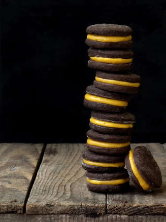 Chocolate sandwich cookies with orange cream piled high back on a dark backgroundの写真素材