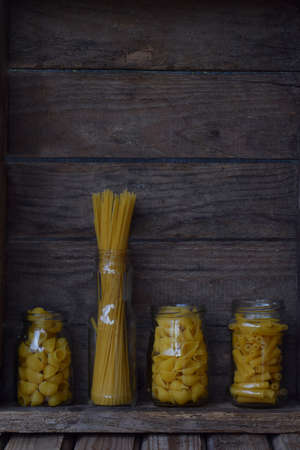 Various mix of macaroni on wooden rustic background. Assortment different kinds of Italian pasta. Diet and food concept. Spaghetti, fettuccine and tagliatelleの写真素材