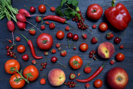 The composition of red vegetarian products: fruits and vegetables on wooden background. Apples, tomatoes, currants, radishes, peppers, raspberries, sweet cherry. Healthy foodの写真素材