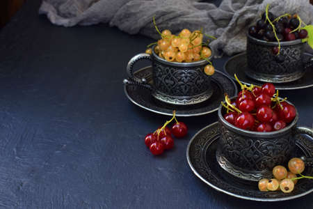 Composition of fresh ripe berries: red, black and white currants on a dark gray concrete background....