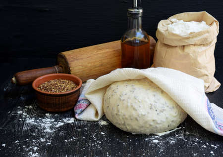 Preparation of homemade bread from whole wheat flour and flax seeds on a dark wooden background. Copy space. Photographing with natural light.の写真素材