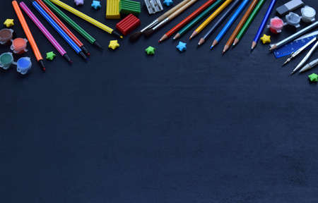 School accessories and supplies: pencils, markers, paints, pens, blackboard for inscriptions on a dark background. Back to school. View from above. Flat lay.の写真素材