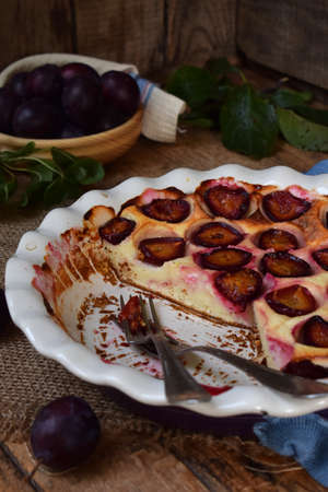Plum pie in white ceramic form on a wooden background. Homemade bakingの写真素材
