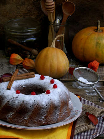 Pumpkin Bundt cake with cranberries and spices sprinkled with powdered sugar on wooden background. Homemade autumn bakingの写真素材