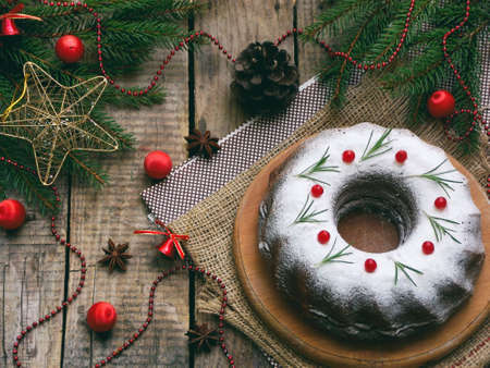 homemade christmas cake with cranberry and new year tree decorations frame on wooden table background. Rustic styleの写真素材