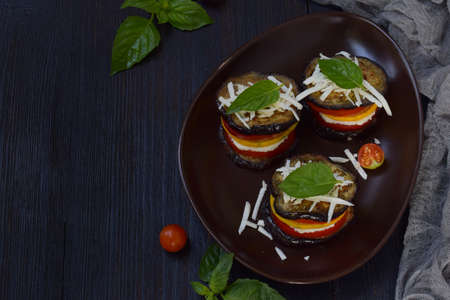 Appetizer from eggplants, zucchini, tomatoes and young cheese on a dark background. Vegetarian food. Ratatouille.の写真素材