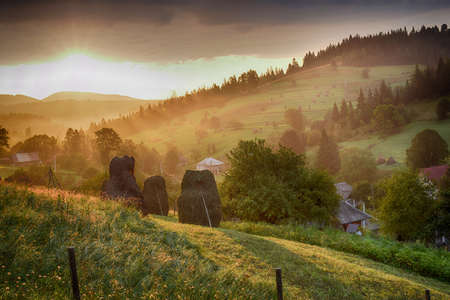 Summer landscape in mountains with traditional hay stacks on hillside. Typical rural scenery of Carpathians.の写真素材