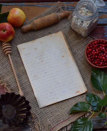 Composition of notepad, apples, cranberries, rolling pin, molds for muffins, oatmeal. Preparation for kneading dough, baking cookie or muffin. Space for text or recipeの写真素材