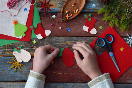 Making of handmade christmas toys from felt with your own hands. Children's DIY concept. Making xmas tree decoration or greeting card. Step 3. Decorate the toy.の写真素材