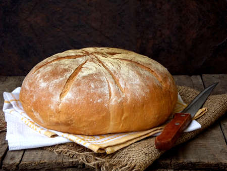 loaf of bread and knife on wooden background