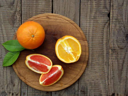 Red and orange juicy oranges on a wooden background. Whole and cut in half. Healthy food.