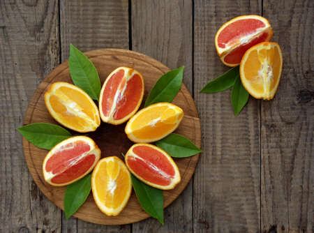 Red and orange juicy oranges on a wooden background. Whole and cut in half. Healthy food.の写真素材