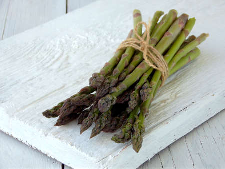 Bunch of fresh green asparagus on light wooden background. Fresh organic vegetables. First spring greens. Healthy food concept. Copy space.の写真素材