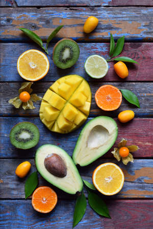 Mix of ripe tropical fruits with avocado, mango, kumquat, kiwi, citrus. Superfood background. Vegetarian raw food. Copy spaceの写真素材