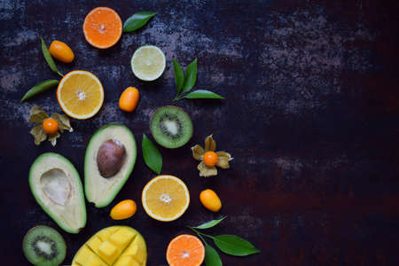 Mix of ripe tropical fruits with avocado, mango, kumquat, kiwi, citrus. Superfood background. Vegetarian raw food. Copy spaceの写真素材