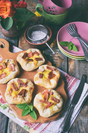 Mini pies made of puff pastry, custard and caramelized rhubarb. Homemade baking. Delicious freshly baked cookies. Rustic photo.の写真素材